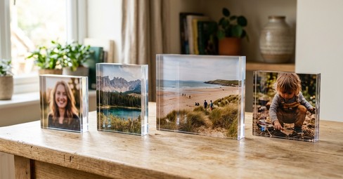 Acrylic photo blocks in several sizes lined up along a wooden shelf