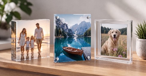 A bright living-room display of acrylic photo products — a chunky freestanding acrylic photo block on a shelf beside a slim, floating acrylic wall print