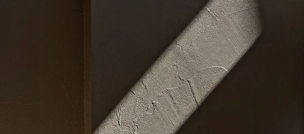 Wall Art Trends. Patch of light in shadow against plastered wall.
