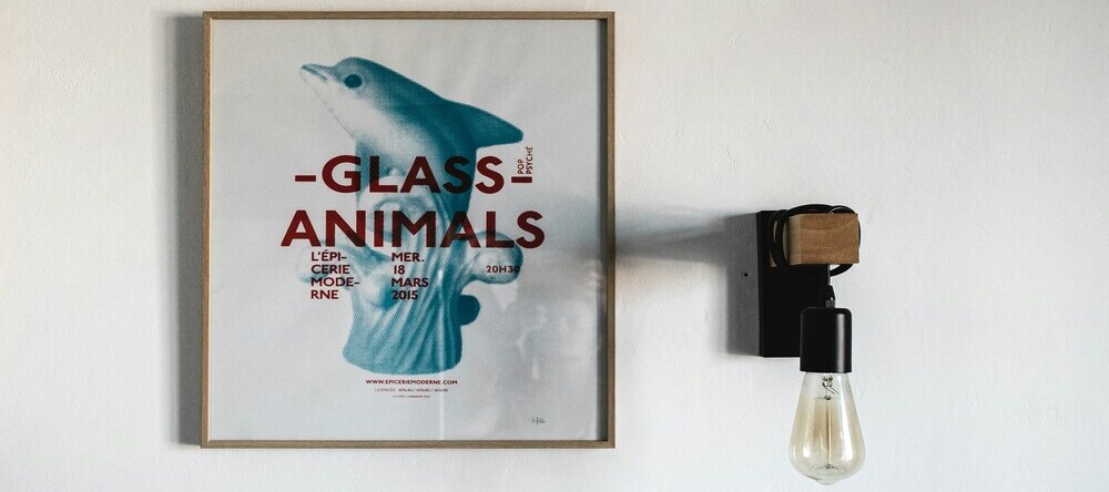 Where Can I Print a Poster? Framed poster on wall next to lightbulb.