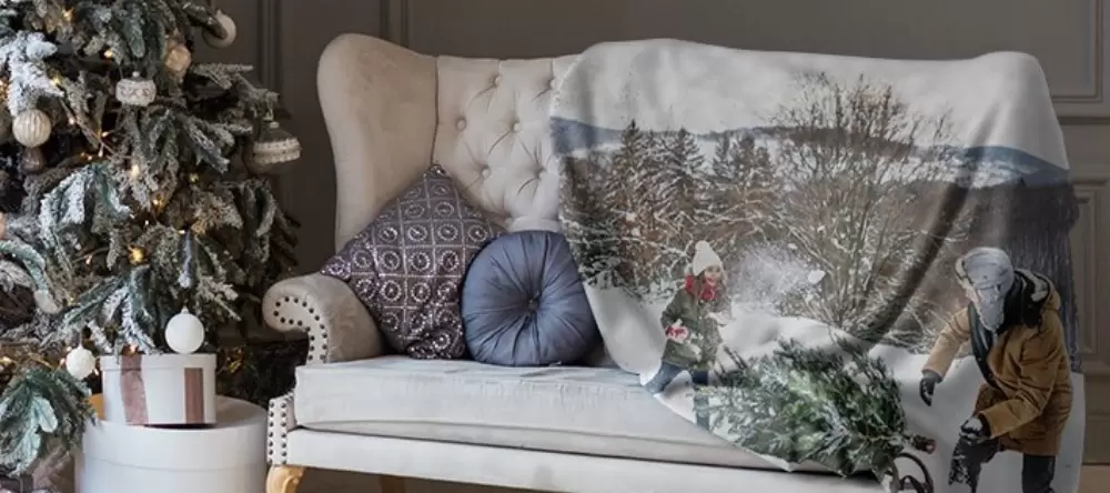 Photo gifts for her. Photo blanket on sofa with Christmas tree next to it.