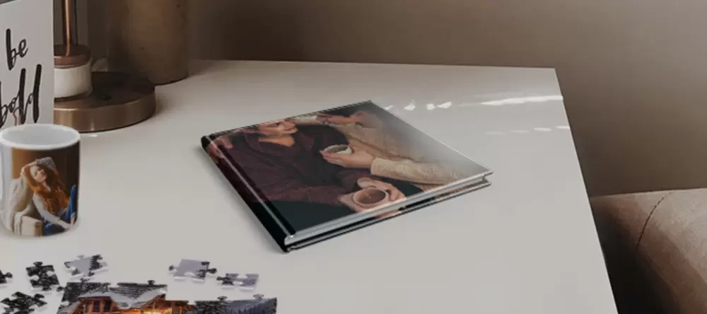 Photo gifts for her. Photo book on table with photo puzzle and personalised photo mug next to it.