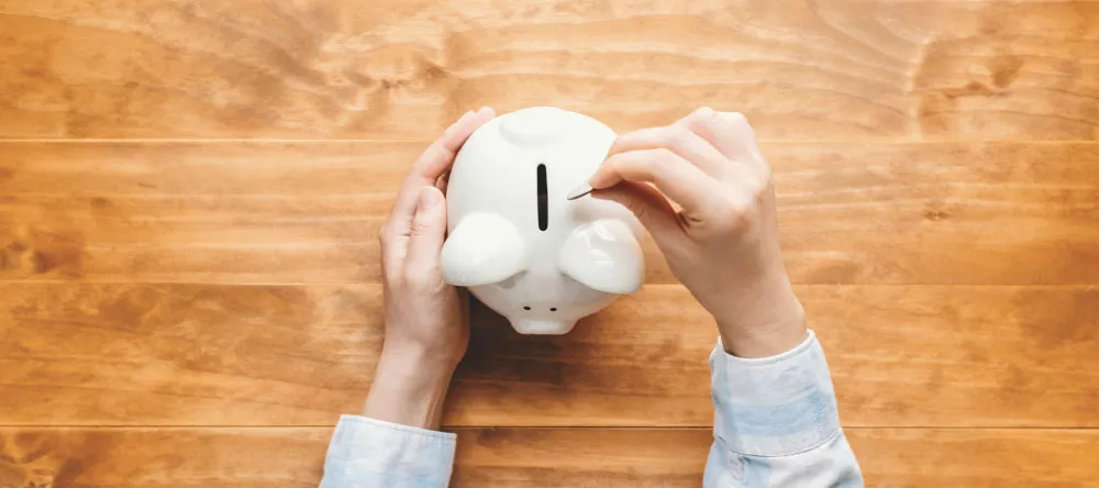 How Much Does a Canvas Print Cost? Man putting coins into piggy bank.