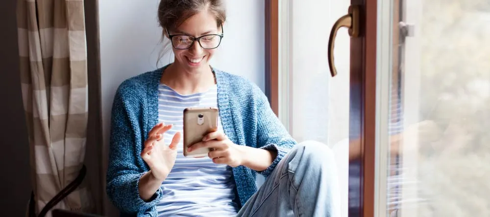 How to Print Pictures from Phone Storage. Happy woman browsing her photo library on phone.