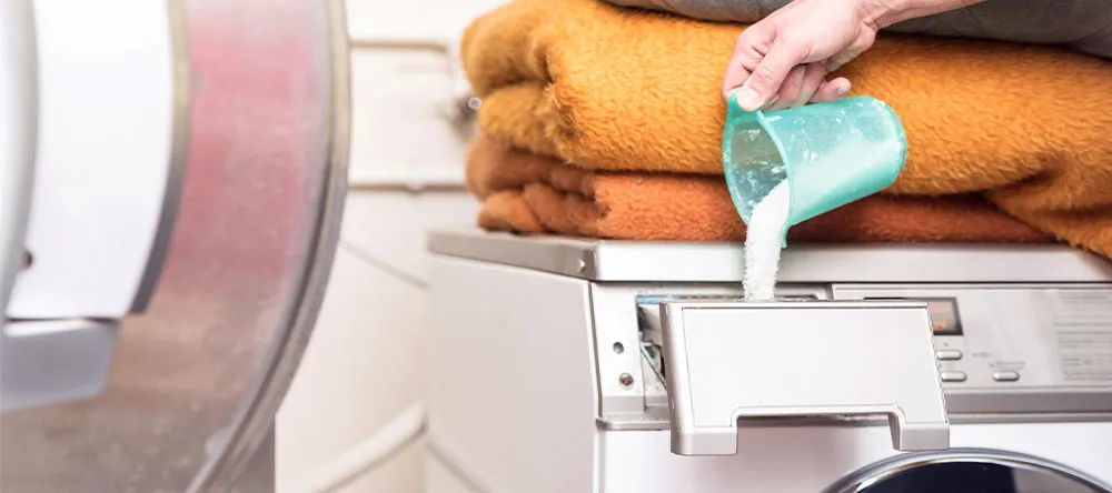 How to Wash a Photo Blanket. Putting washing detergent in washing machine.
