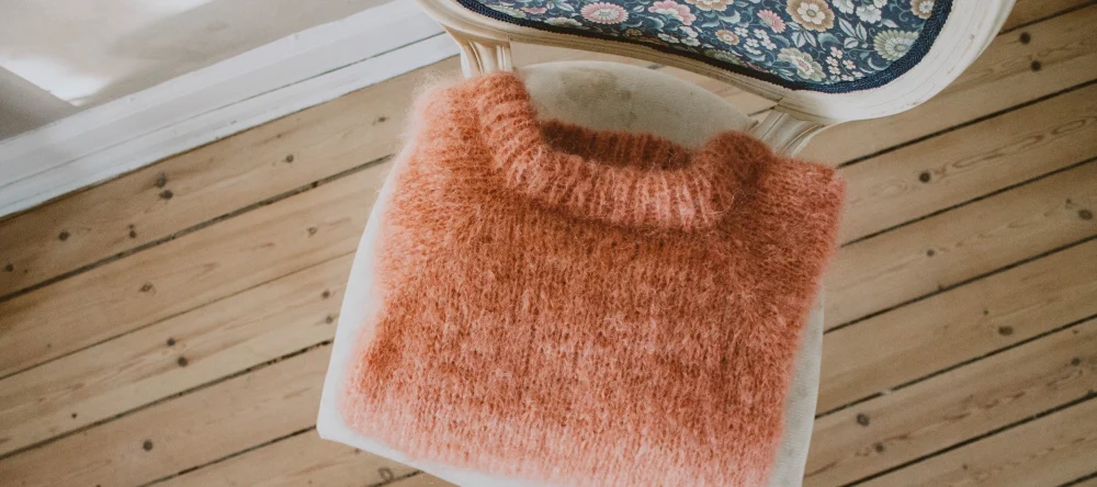 What do you take to a baby shower. A knitted jumper on a chair.