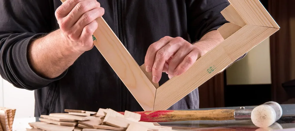Canvas Pictures for Living Room. Craftsman working on wooden frame.