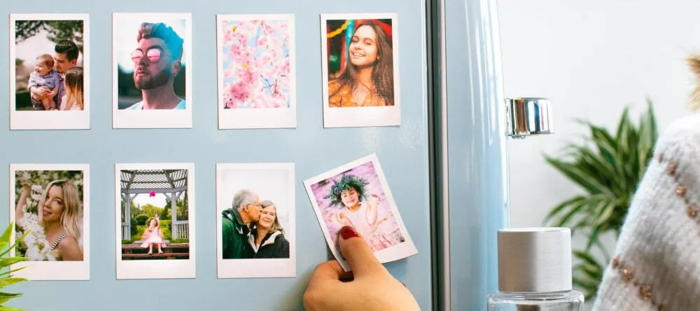 Where can I buy magnets: a person sticking photo magnets to the fridge