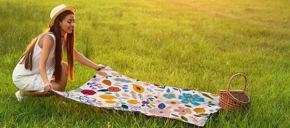 Personalised picnic blanket: a woman spreading out a blanket on the ground