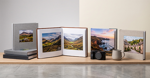 An open layflat photo book on a wooden table showing a full double-page family photo spread