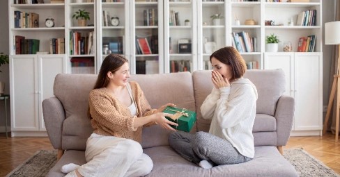 A thoughtfully wrapped personalised birthday photo gift being handed between two close friends