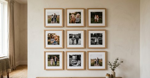 A 3x3 grid of framed family photos hung above a grey sofa in a bright living room