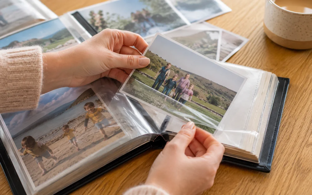 Hands slotting a printed family photo into the clear sleeve pocket of a photo album