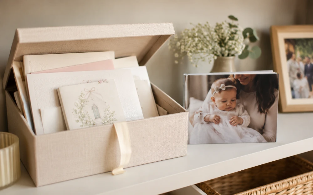 Keepsake box filled with christening cards beside a photo book of a mother and baby in a christening gown