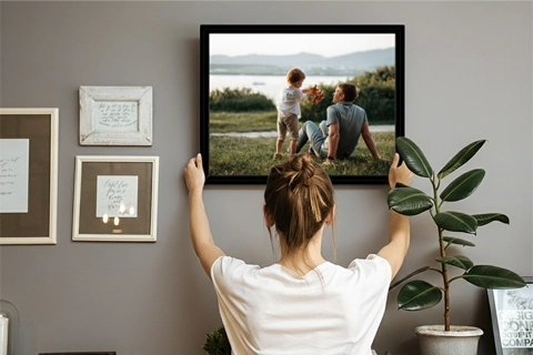 woman placing framed canvas with a picture of a dad and a son